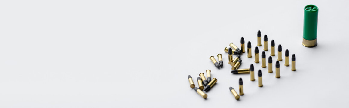same caliber bullets near shotgun shell on white, banner.