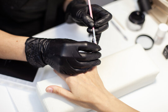 Manicurist Glue False Nails To A Woman Client In A Nail Salon. The Working Process