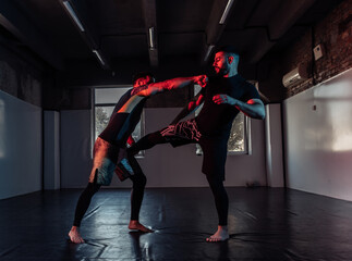 Fototapeta na wymiar MMA fighters train kicks and defense in neon light at sports hall