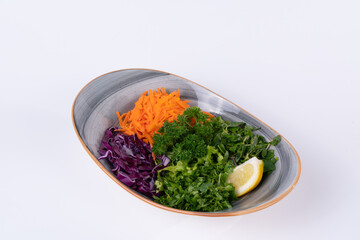 Cropped view of salad made of parsley, arugula, collard greens and grated carrots shot from opposite or side view on isolated white background.