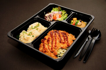 bento box with cutlery and knife on black background, isolated