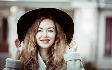 Portrait of smiling pretty woman with braces and felt hat outdoors