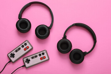 Stereo headphones with retro gamepads on pink background. Time to play. Video game. Gaming concept