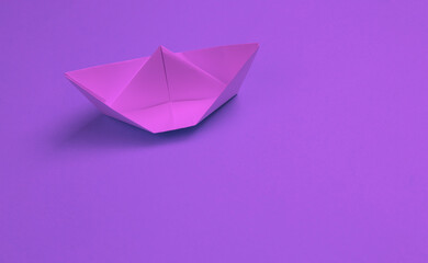 Paper origami boat on a pink background. Neon light