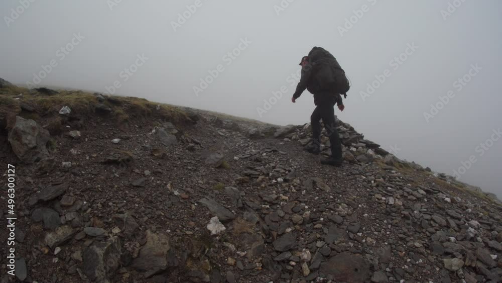 Canvas Prints A hiker in terrible weather putting a rock on a stone cairn