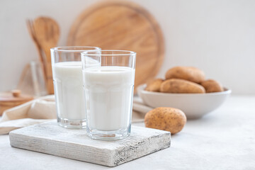 Potato milk on a white background with potatoes. Vegetarian lactose-free milk. Side view.