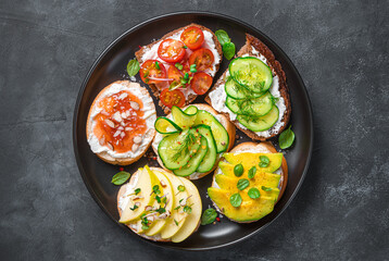 Crostini with feta, ricotta and various vegetables and fruits. Top view, close-up.