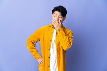 Young Chinese man isolated on purple background doing surprise gesture while looking to the side
