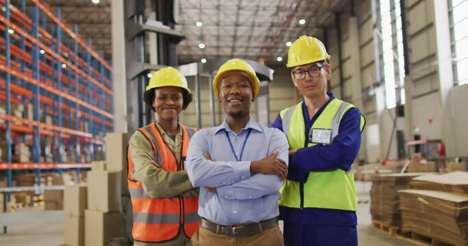 Portrait of diverse workers wearing safety suits and smiling in warehouse