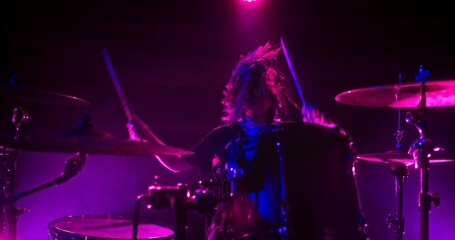 Fototapeta na wymiar Professional drummer girl plays drum kit perfectly on stage during rock concert