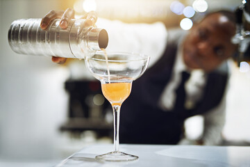 Hes always updating his craft. Cropped shot of a bartender making a cocktail.