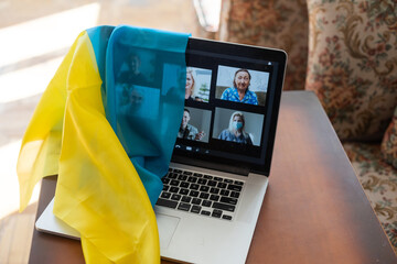Flag of Ukraine on the background and wide digital screen of laptop with video conference. War with Russia. Cyber attack, sanctions, economic collapse. Message for world peace.