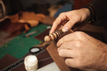 tanner makes genuine leather wallet, professional craftsman, closeup, indoor, authentic, business. Handiwork. wooden tool