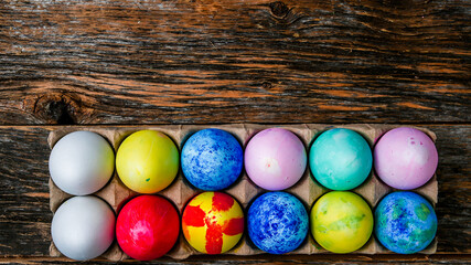 Painted and colored Easter eggs on rustic wooden table inside paper container