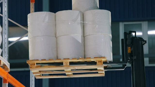 The forklift puts the goods on the shelf of the warehouse. The forklift puts the nonwovens on the shelf of the factory warehouse. Warehouse at the nonwovens factory.