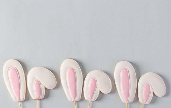 Gingerbread cookies in the shape of bunny ears on a pastel blue background. View from above