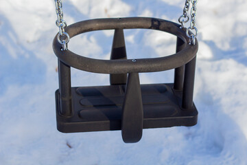 Swing on the children playground in winter with snow