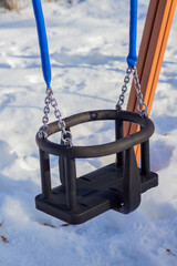Swing on the children playground in winter with snow