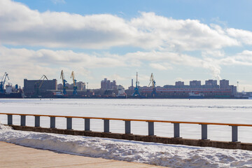 View of the port with cranes in winter from the river bank, industrial area