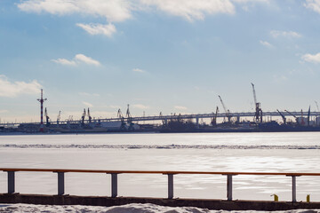 View of the port with cranes in winter from the river bank, industrial area