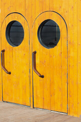 Wooden brown door entrance exit in nautical marine style with a porthole on an old vintage ship boat