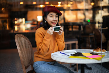 Beautiful Chinese woman drinking coffee in cafe. Young smiling woman enjoy in restaurant.