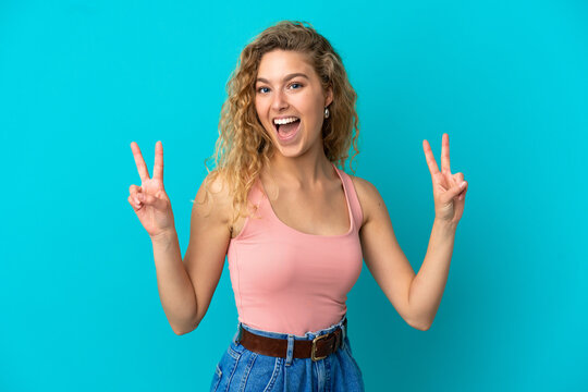 Young blonde woman isolated on blue background showing victory sign with both hands