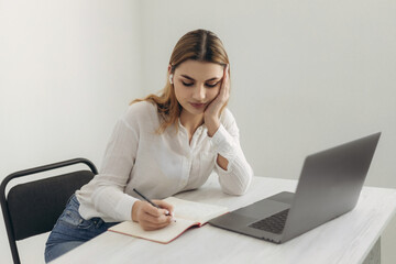 A young beautiful girl in headphones learns with internet chat, a Skype teacher prepares for an...