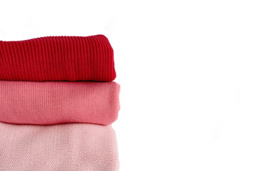 Różowe swetry ułożone w stos. Zdjęcia na białym tle z wolną przestrzenią.