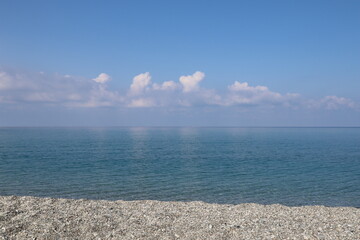 Obraz premium Sea and sky, beach and clear blue sea and clear sky with white clouds on a sunny morning. Calabria, Tyrrhenian coast, Italy