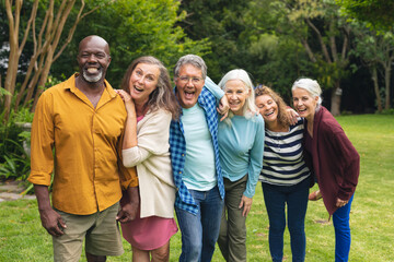 Portrait of happy multiracial senior male and female friends enjoying in backyard