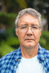 Portrait of confident caucasian senior man with eyeglasses in backyard on weekend