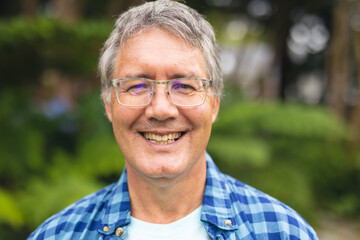 Portrait of smiling caucasian senior man standing in backyard on weekend