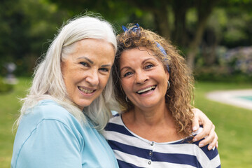 Portrait of happy caucasian senior female friends spending leisure time together in backyard