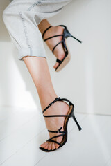 Black high heel sandals. Fashionable beautiful young woman in a black high heel sandals. Stylish cute happy girl in the room. Spring. Summer. close-up. - obrazy, fototapety, plakaty