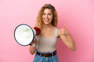 Young blonde woman isolated on pink background holding a megaphone with thumb up