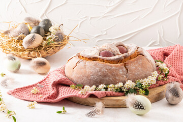Portuguese traditional Easter cake with eggs. Typical Folar de Vale de Ilhavo, Aveiro, Portugal. Blossom flowers and colorful painted eggs decorated with feathers on easter table.