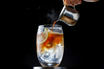 delicious alcoholic cocktail with hot coffee and ice on a dark background, close-up bartender pours...