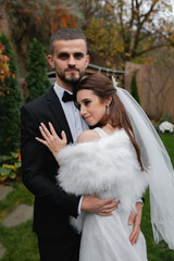 Young cheerful wedding couple. A bride with a veil, a charming groom in a black suit.