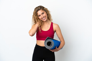 Young sport blonde woman going to yoga classes while holding a mat isolated on white background laughing