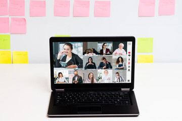 Fototapeta na wymiar Corporate video call. Online teamwork. Virtual business meeting. Employees brainstorming in digital office on laptop screen at white workplace with sticky notes free space.