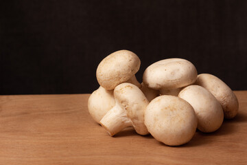 photograph of champignons on a wooden cutting board on a dark background with empty space