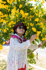 Asian Seniors Woman Wear Glasses And Hat Standing Among Yellow Flowers