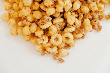 Dry muesli with cornflakes, nuts and raisins on a white background