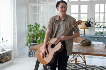 Portrait of a musician man holding guitar in home Studio