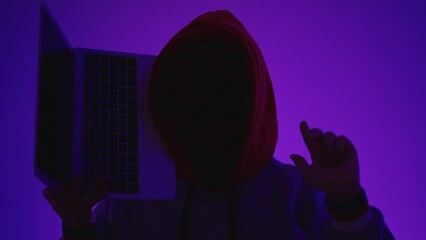 Anonymous Hacker Holding Laptop In A Dark Room With Neon Lights.