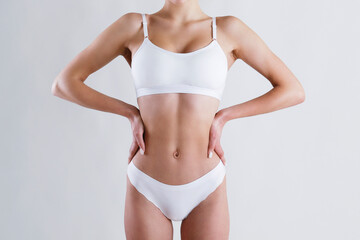 Fototapeta na wymiar Close up shot of unrecognizable fit woman in lingerie isolated on white background. Torso of slim attractive female with flat belly in white underwear. Copy space for text.