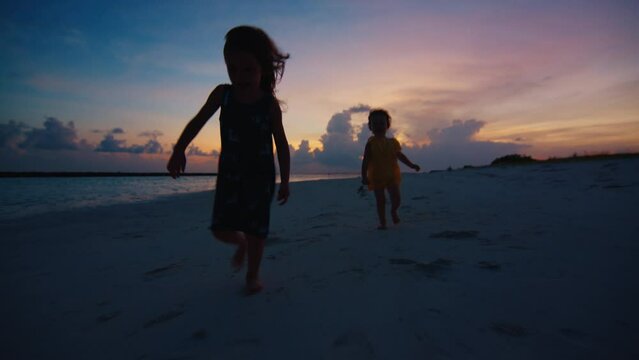 Kids run on the tropical beach at sunset