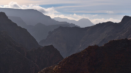 Panoramic view with landscape of the silhouettes of mountains in the west of Gran Canaria, Spain near road GC-210 on misty day with steep ravine.
