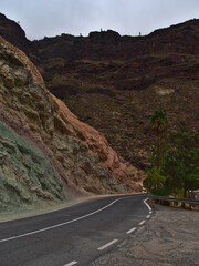 Landscape with colorful volcanic rocks at Los Azulejos De Veneguera in the western mountains of Gran Canaria, Canary Islands, Spain with rural road.